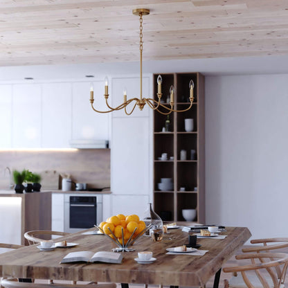 Annabelle 30-inch wide 6-light chandelier in satin brass featuring a steel frame with gracefully curved arms, candelabra-style bulbs, and chain suspension, shown installed in a styled interior setting.